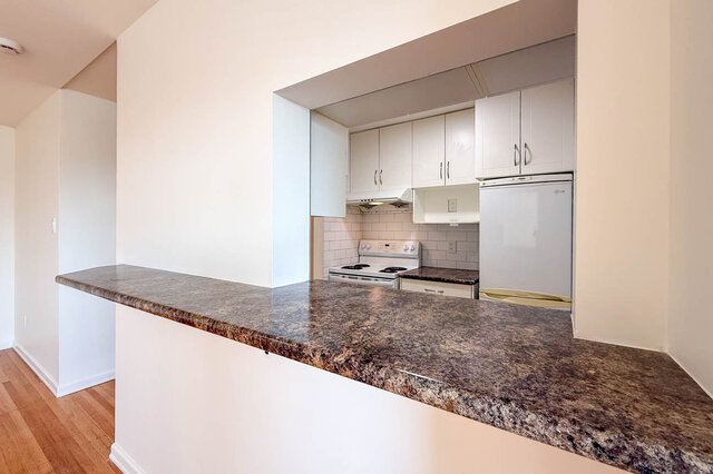 The pass-through counter from the living room, looking into the kitchen with its white stove and fridge - 107-461-16th Street West, North Vancouver
