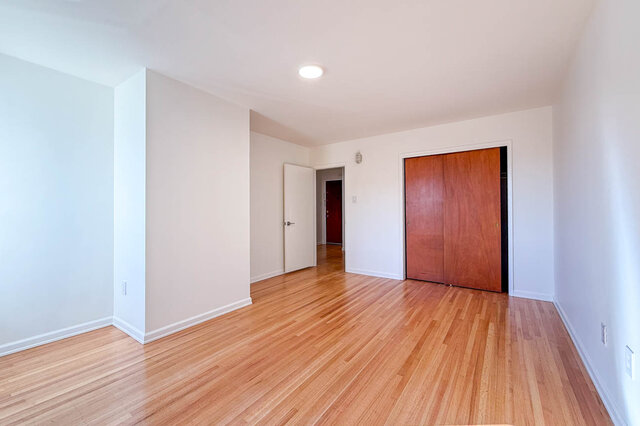 The larger bedroom with a sliding wood closet and the door to the hall - 107-461-16th Street West, North Vancouver
