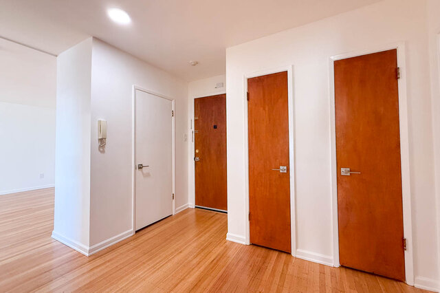 The entry hall with the front door, two hall closets and an intercom, on hardwood floors - 107-461-16th Street West, North Vancouver
