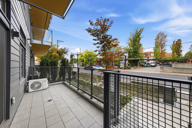 Private fenced patio with paver tiles at street level, trees along the road beyond. - 111-1529 Oxford Street, North Vancouver