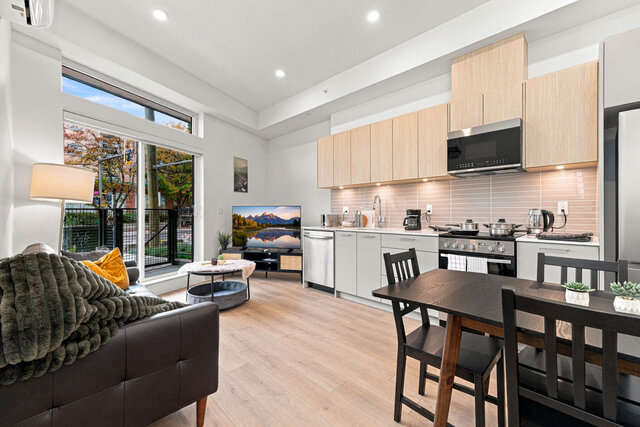Living room with the patio door and transom glass, the kitchen and dining table to the right. - 111-1529 Oxford Street, North Vancouver