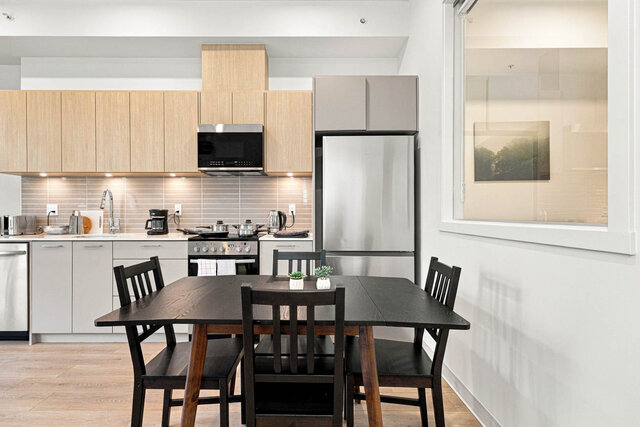 Dining table for four in front of the kitchen and stainless fridge. - 111-1529 Oxford Street, North Vancouver