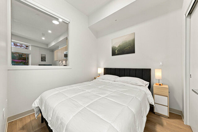 Second bedroom with a made-up queen bed, a sliding closet and an inside window to the living room. - 111-1529 Oxford Street, North Vancouver