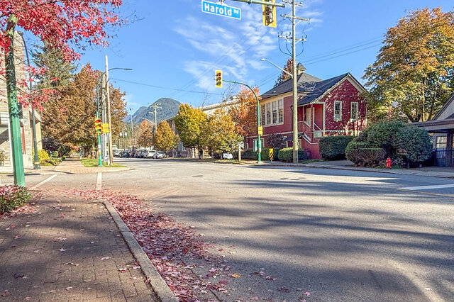 Corner of Harold Road with autumn trees, a red heritage-style house and the mountains behind. - 402-3205 Mountain Highway, North Vancouver
