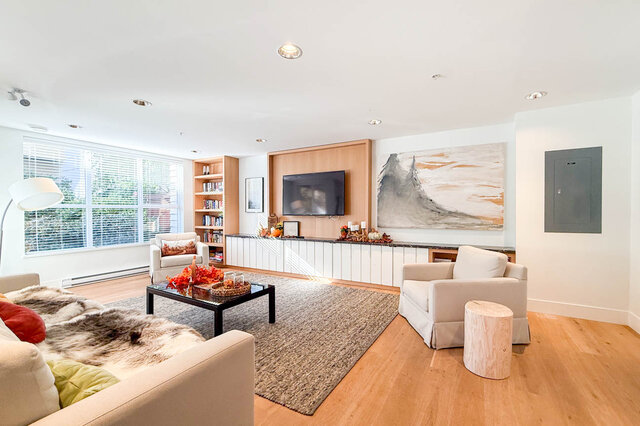 Resident lounge seating area with a wall-mounted TV, bookshelves and armchairs. - 402-3205 Mountain Highway, North Vancouver