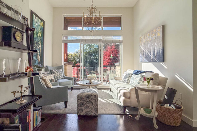 Living room with a sofa and two armchairs facing tall sliding glass doors to the balcony, a chandelier above.