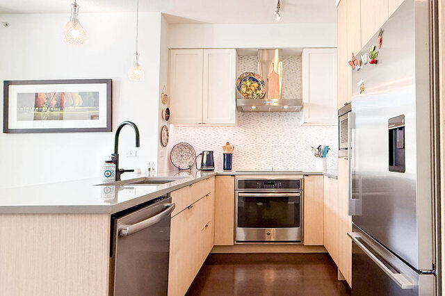 Kitchen with a wall oven, a stainless range hood, a tile backsplash and a dishwasher. - 402-3205 Mountain Highway, North Vancouver