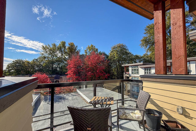 Balcony seating under a covered timber roof, looking out to tall trees. - 402-3205 Mountain Highway, North Vancouver