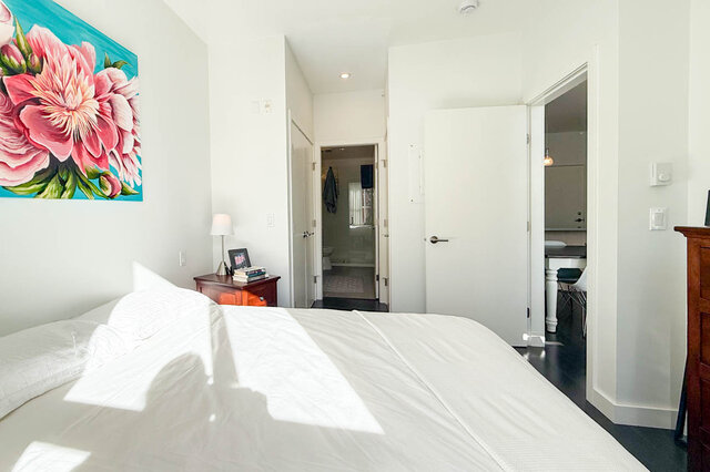 Primary bedroom with the queen bed, a closet door and the door through to its ensuite bathroom. - 402-3205 Mountain Highway, North Vancouver