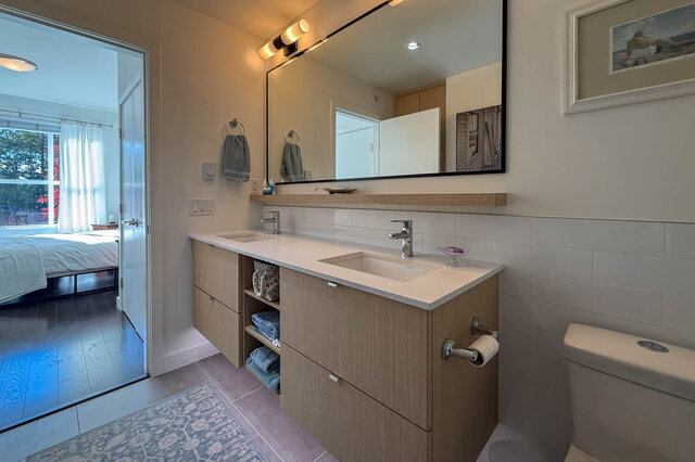 Ensuite double vanity with a wide mirror, the primary bedroom through the door. - 402-3205 Mountain Highway, North Vancouver