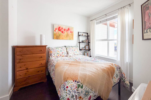 Second bedroom with a double bed, a wood dresser and a window with white curtains. - 402-3205 Mountain Highway, North Vancouver
