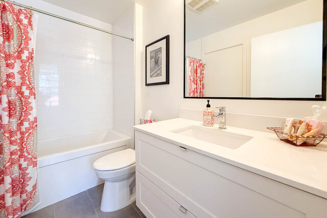 Second ensuite bathroom with a tub and shower, white subway tile and a white vanity. - 402-3205 Mountain Highway, North Vancouver