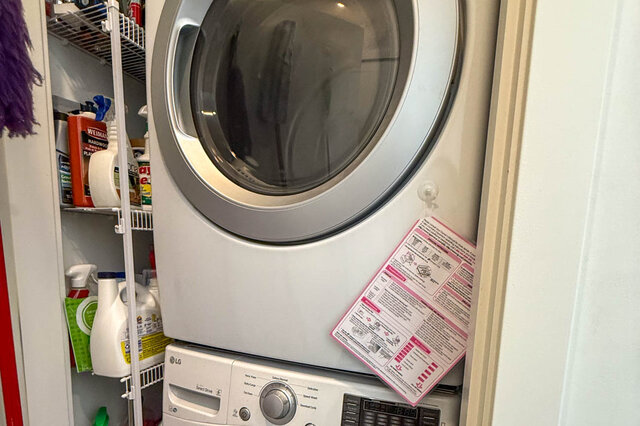 Stacked LG washer and dryer in a closet with shelves. - 402-3205 Mountain Highway, North Vancouver