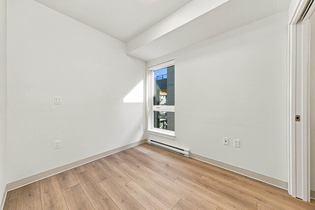 Primary bedroom with a tall window, a sliding closet and hardwood floors. - 525-1529 Oxford Street, North Vancouver