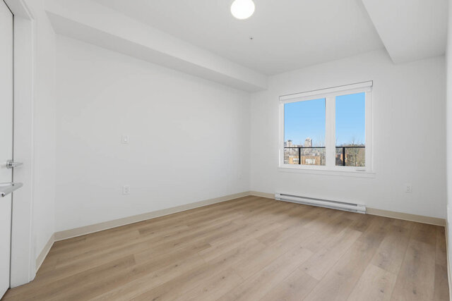 Primary bedroom with a wide window out past the balcony railing to the towers. - 619-1529 Oxford Street, North Vancouver