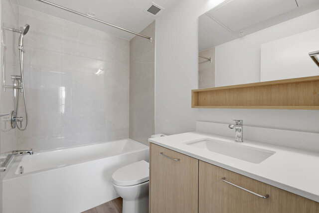 Second full bathroom with a tub and shower, a tile surround and a light wood vanity with a quartz counter. - 619-1529 Oxford Street, North Vancouver