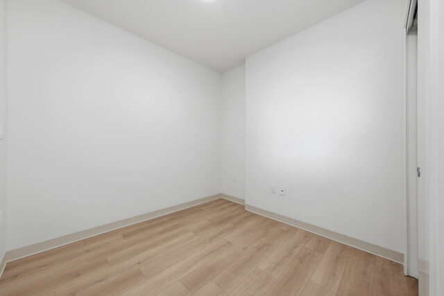 Empty bedroom corner with a sliding closet and hardwood floors. - 619-1529 Oxford Street, North Vancouver