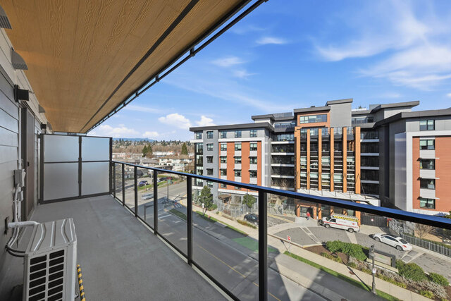 Covered balcony with a wood ceiling, a frosted privacy screen and a glass railing, looking along the street to the neighbouri