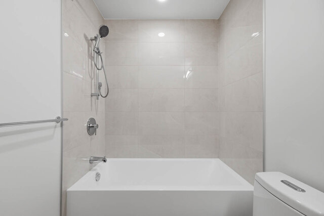 Close view of the tub and shower with a handheld shower head and a tile surround. - 424-1529 Oxford Street, North Vancouver