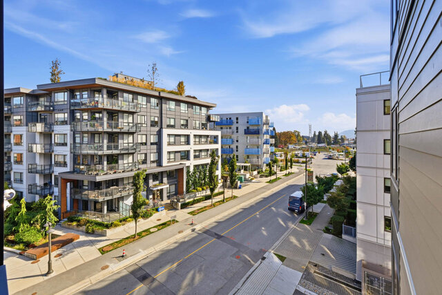 Looking down from the balcony over the tree-lined street to the neighbouring buildings, with mountains far off on the right.