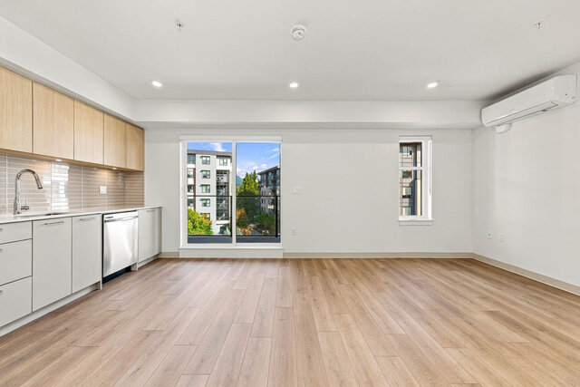 Living and dining area with the kitchen counter on the left, the sliding glass door to the balcony, a second window and a wal
