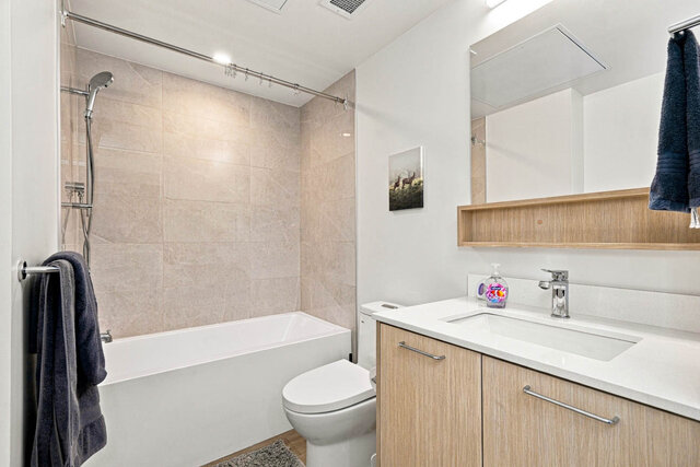 Second full bathroom with a tub and shower, a tile surround and a light wood vanity with a quartz counter. - 224-1529 Oxford Street, North Vancouver