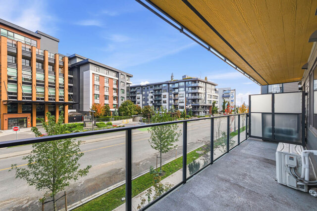 Covered balcony running the width of the suite, with a wood ceiling and glass railing over the tree-lined street and the neig