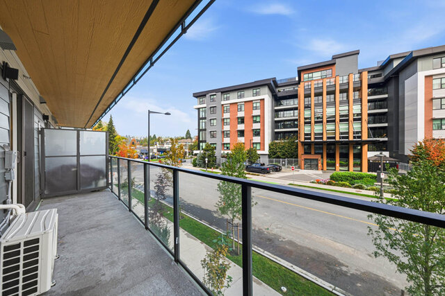 Covered balcony with a wood ceiling, a frosted privacy screen and a glass railing over the street. - 224-1529 Oxford Street, North Vancouver