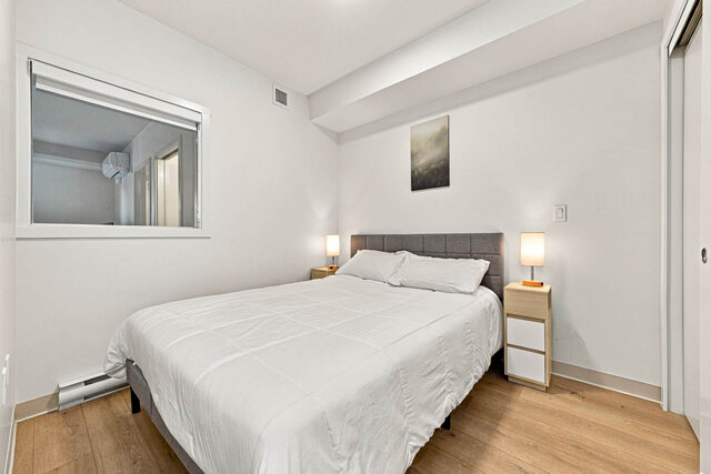 Primary bedroom with a queen bed, a grey upholstered headboard, nightstands with two lamps, a sliding closet and an interior 
