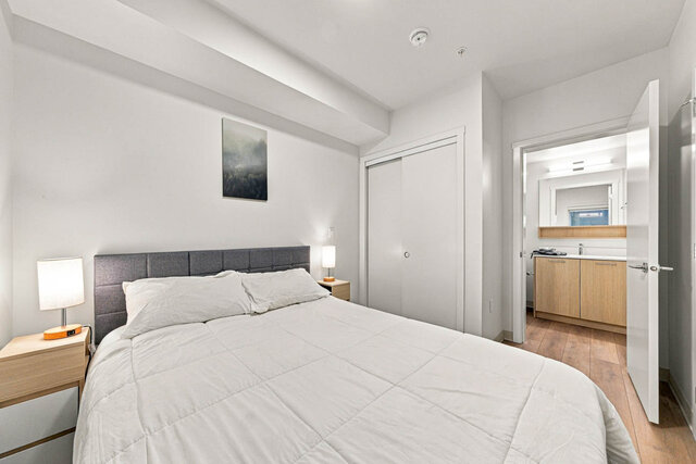 Primary bedroom with a queen bed, a sliding closet and an open door to its ensuite with a light wood vanity. - 224-1529 Oxford Street, North Vancouver