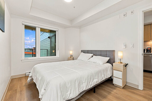 Primary bedroom with a bed, an upholstered headboard, nightstands and lamps, and a window onto the covered balcony.