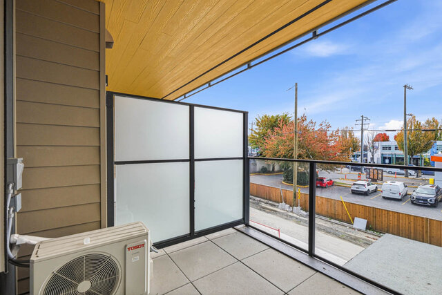 Covered balcony with a wood ceiling, tile floor, a frosted privacy screen and a glass railing over the street and autumn tree