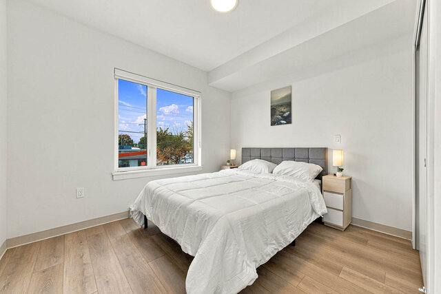 Second bedroom with a bed, an upholstered headboard, nightstands and lamps, a big window and a sliding closet.