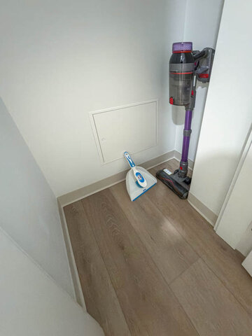 Small closet holding a cordless vacuum and a dustpan. - 101-1529 Oxford Street, North Vancouver