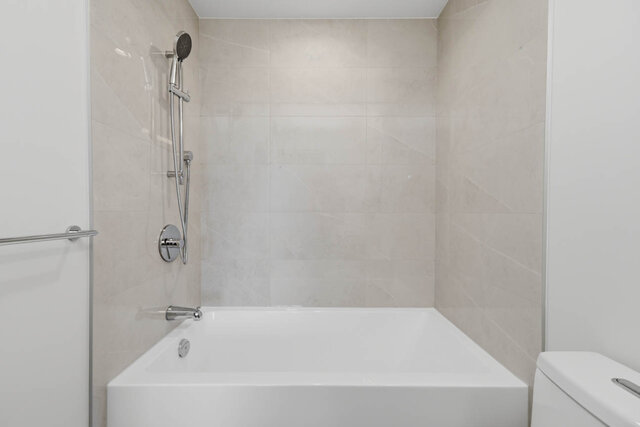 Tub and shower with a handheld shower head and tile surround. - 518-1529 Oxford Street, North Vancouver