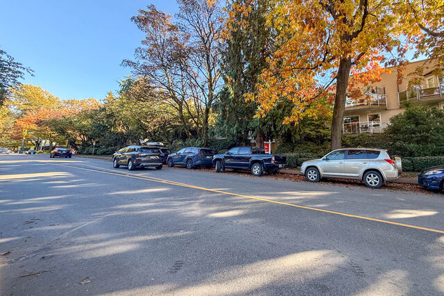 Tree-lined residential street in autumn colour, with the building and its balconies on the right. - 304-827 West 16th Street, North Vancouver