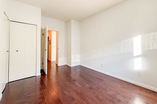 Bedroom with a closet and sunlight across the wall, hardwood floors. - 304-827 West 16th Street, North Vancouver