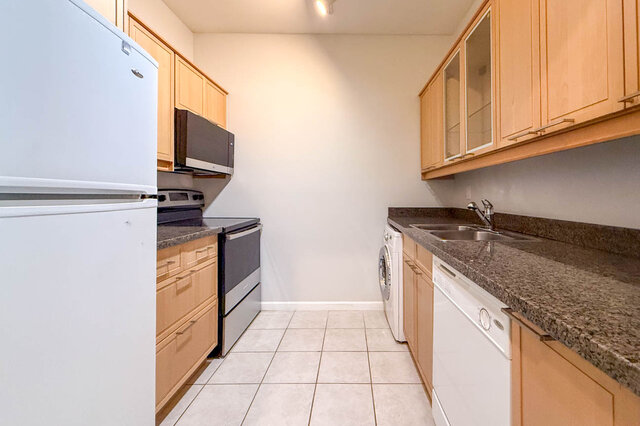 Galley kitchen with wood cabinets, granite countertops, a new electric range and microwave, a dishwasher and a washer-dryer, 