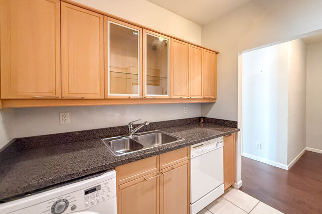 Kitchen with glass-front wood cabinets, granite countertops, a double sink and a dishwasher, opening to the hall.