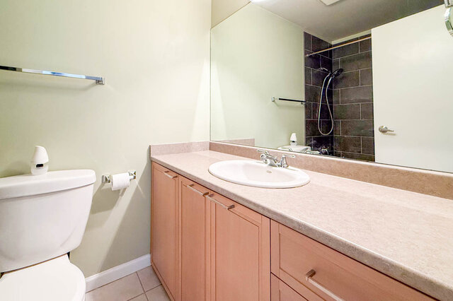 Bathroom with a long wood vanity, a large mirror and tile floors. - 304-827 West 16th Street, North Vancouver