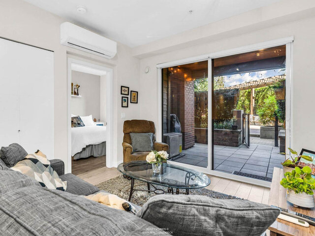 Living room with the bedroom through the doorway on the left and sliding glass doors to the covered patio; an air conditionin