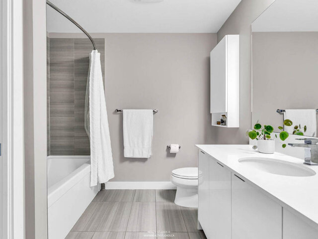 Bathroom with a tub and shower, a tiled wall, a white vanity and a wall cabinet. - 117-723 3rd street West, North Vancouver
