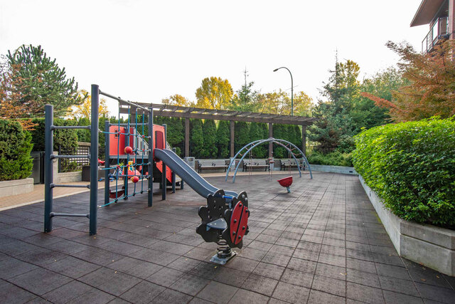 Shared playground with a play structure and slide, a pergola and benches along the hedges. - 117-723 3rd street West, North Vancouver