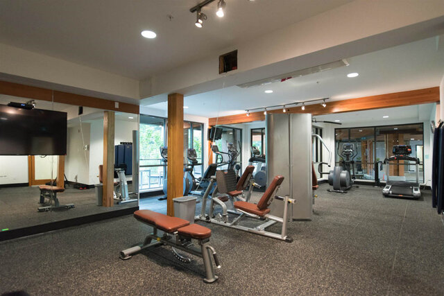 Shared building gym with treadmills, ellipticals, weight machines and a mirrored wall. - 117-723 3rd street West, North Vancouver