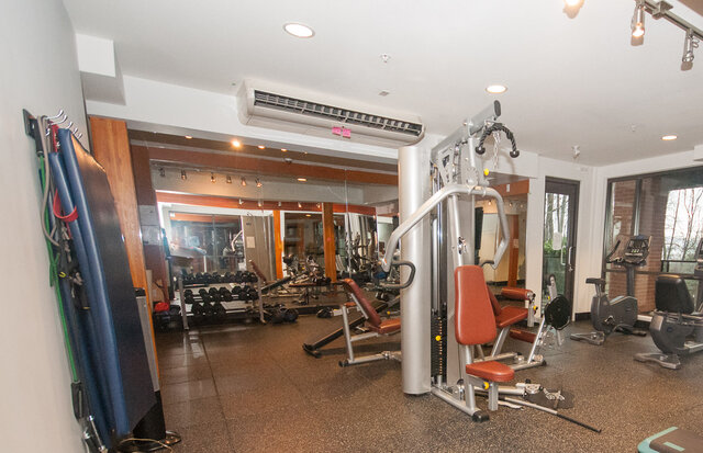 Shared building gym with a cable machine, exercise bikes and a dumbbell rack. - 117-723 3rd street West, North Vancouver
