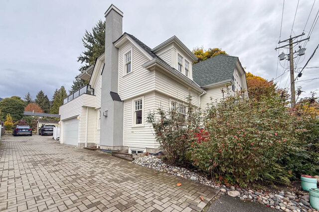 Side of the house with the garage, a paver driveway and the upper deck above the garage. - North Vancouver