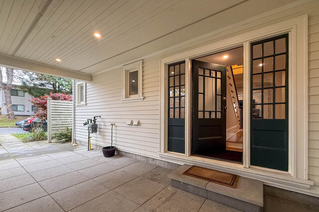 Covered side porch with glass-paned double doors open to the stairs inside. - North Vancouver