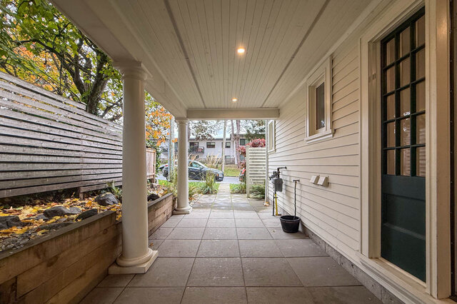 Covered side porch with columns, garden beds and a walkway to the street. - North Vancouver