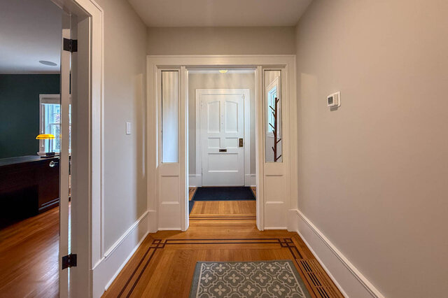 Front hall with inlaid hardwood floors, glass side panels and the front door, the office on the left. - North Vancouver