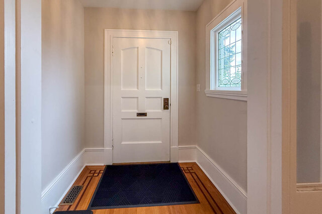 Front entry with a panelled door, a leaded glass window and inlaid hardwood floors. - North Vancouver